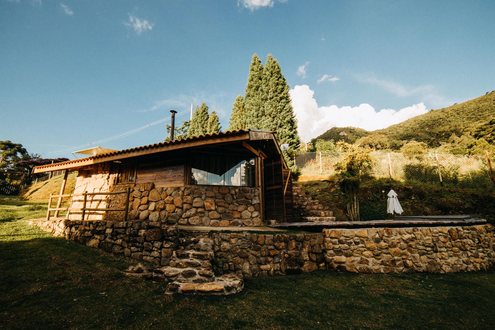 A low stone-and-timber cabin with steps and a terrace against the hillside