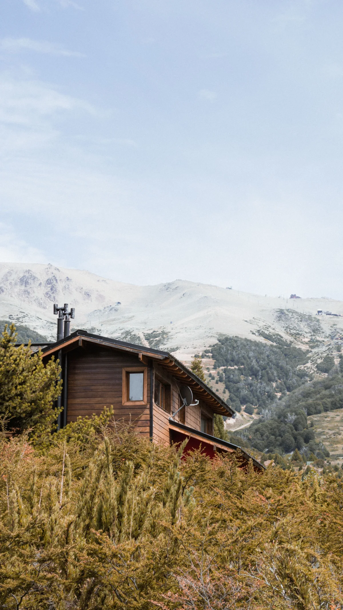A small timber cabin below snow-covered mountains